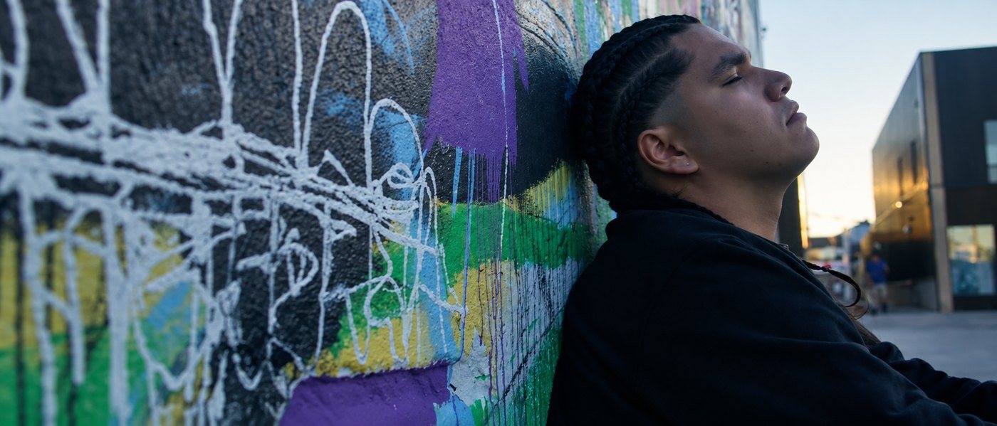 J. Otis leaning against a graffiti wall in the Do or Die music video